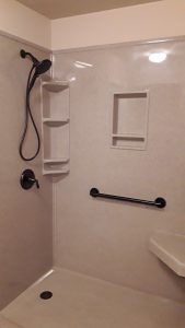 Shower outfitted with a seat, grab bar, and shelving 