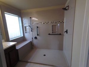 A large walk-in shower for seniors that is equipped with seating and safety grab bars